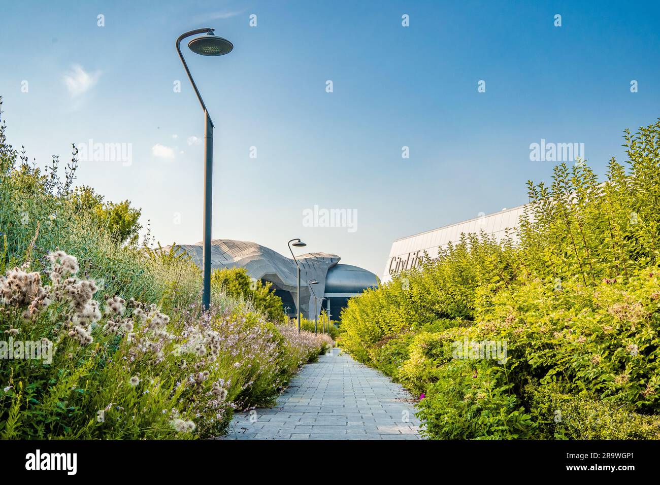 Ein blühender Pfad im Park mit dem Milano Convention Center namens „Allianz MiCo“ im Hintergrund, CityLife-Viertel, Mailand, Italien Stockfoto