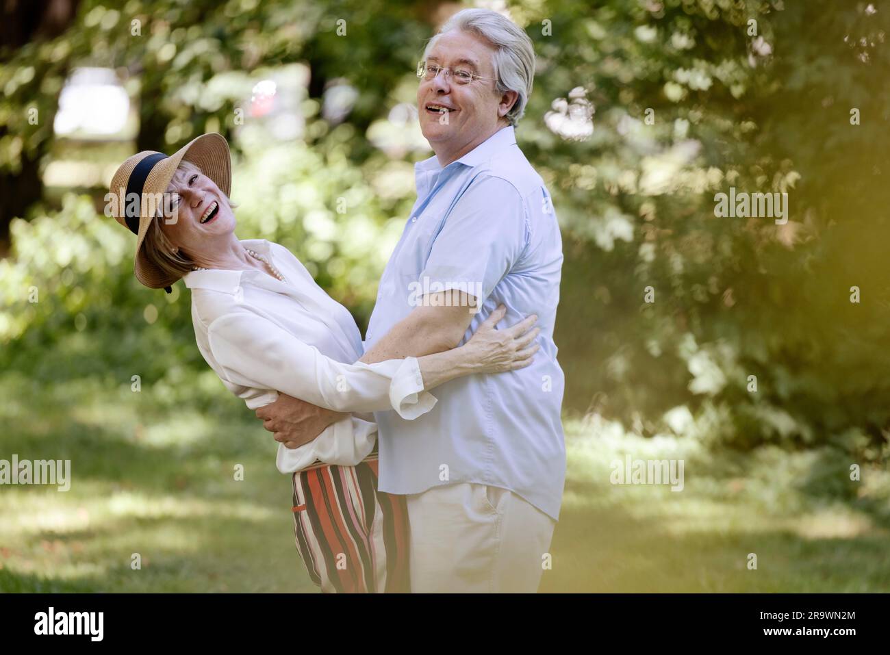 Deutschland, ein älteres Paar, das für den Sommer gekleidet ist, sich umarmt und Spaß in der Natur hat Stockfoto