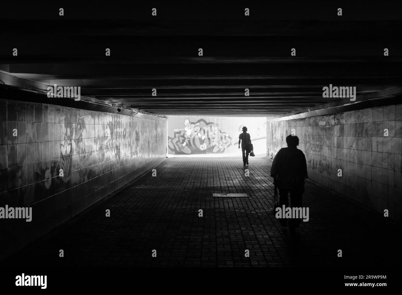 KIEW UKRAINE - 26. MAI 2012 - zwei Personen, die eine dunkle Unterführung mit Fußball-Graffiti benutzen, um die FUSSBALL-EUROPAMEISTERSCHAFT 2012 in Kiew zu veranschaulichen Stockfoto