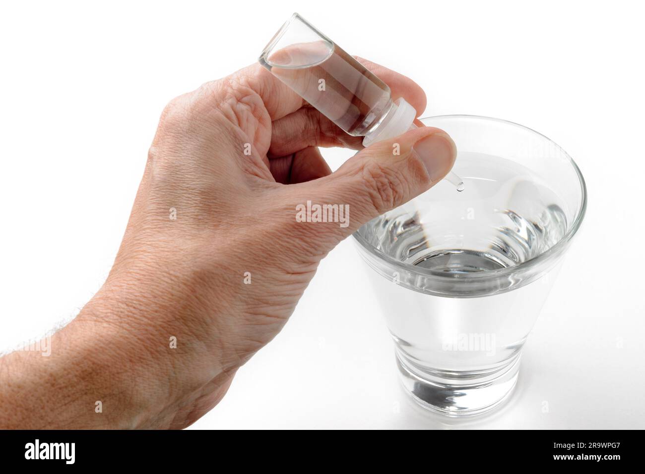 Die Hand des Menschen setzen Apotheke Tropfen in ein Glas transparent Wasser auf weißem Hintergrund Stockfoto