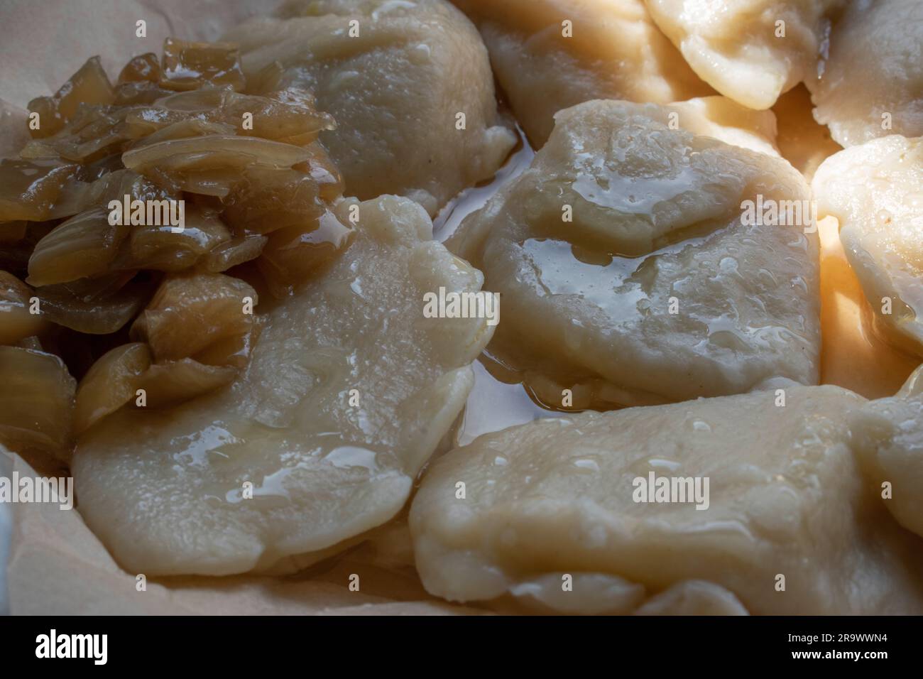 Authentische polnische Pierogi, perfekt gekocht, begleitet von karamellisierten Zwiebeln auf einem Teller, die die herzhaften und beruhigenden Qualitäten dieses Teers zeigen Stockfoto