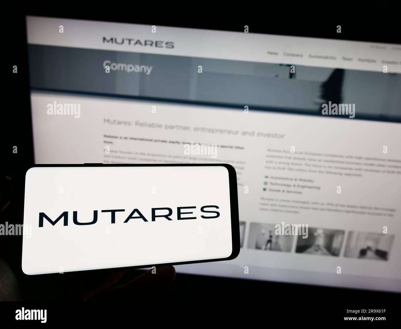 Person, die ein Mobiltelefon mit dem Logo der deutschen Investmentgesellschaft Mutares SE Co. Hält KGaA auf dem Bildschirm vor der Webseite. Konzentrieren Sie sich auf das Display des Telefons. Stockfoto