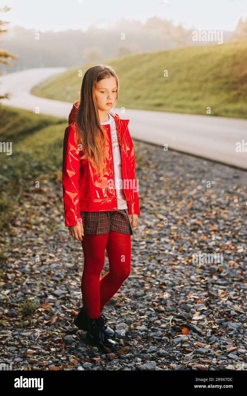 Außenporträt eines hübschen Mädchens mit roter Jacke, modisches Kindermodel Stockfoto