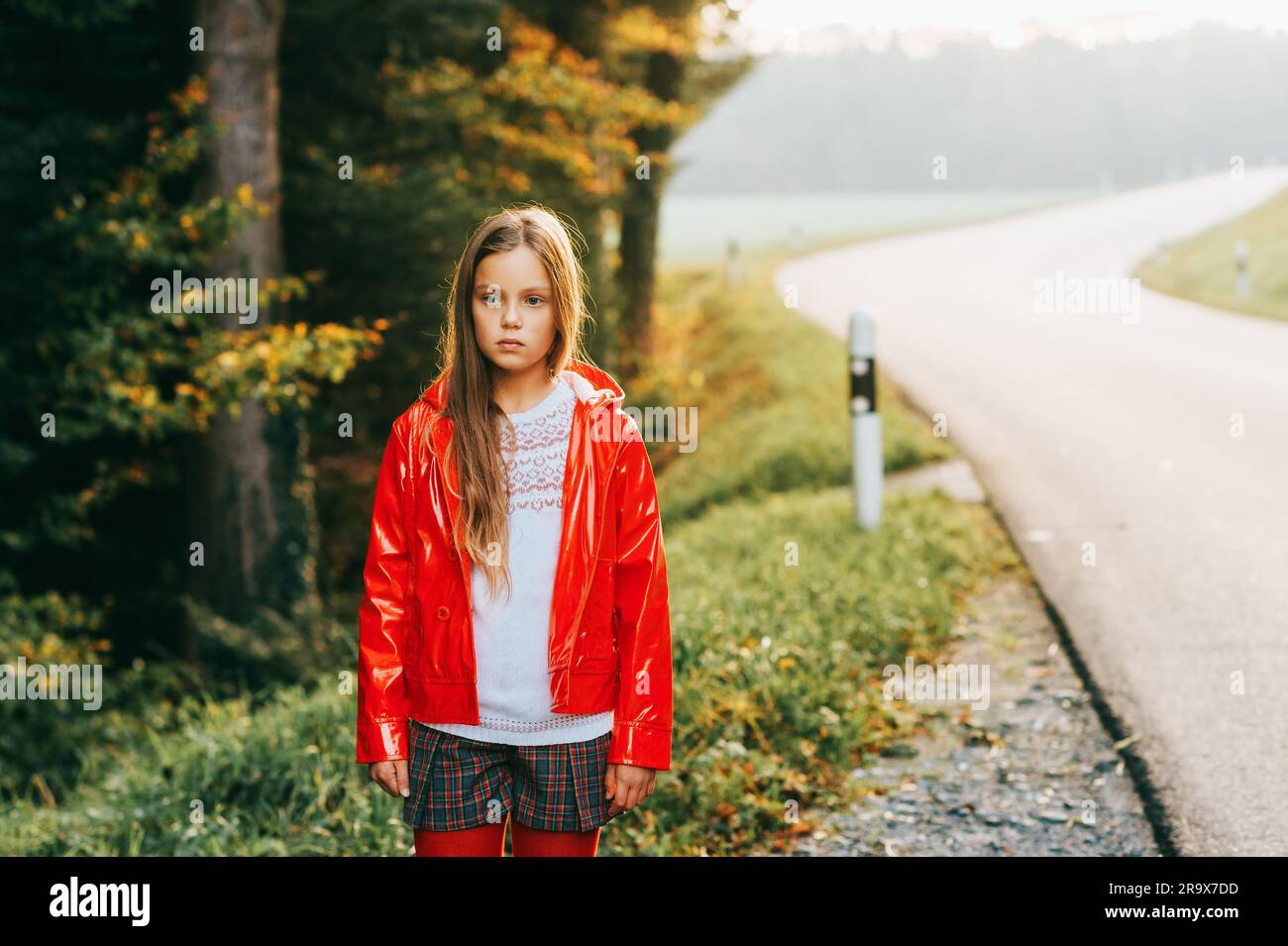 Außenporträt eines hübschen Mädchens mit roter Jacke, modisches Kindermodel Stockfoto