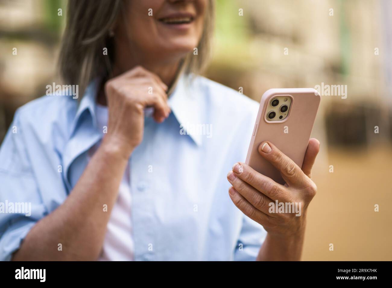 Hände einer Seniorin, die ein Handy hält, unter Betonung des Kommunikationskonzepts im Alter. Das Bild zeigt die Finger der Frau, während sie eine Nachricht am Telefon schickt, und unterstreicht ihre Verlobung mit moderner Technologie. . Hochwertiges Foto Stockfoto