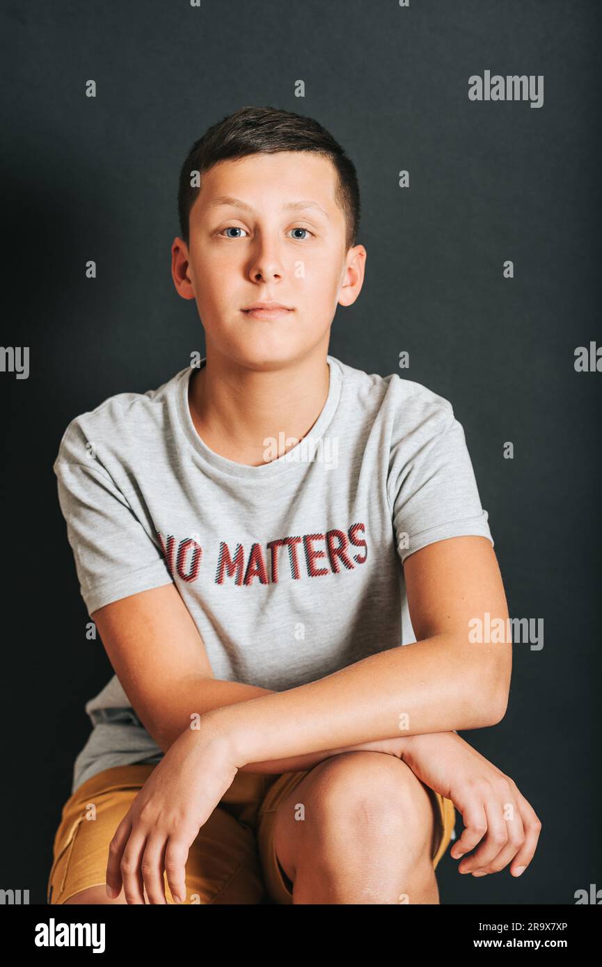 Studioaufnahme eines jungen Teenagers, der auf schwarzem Hintergrund posiert und ein T-Shirt mit dem Schild „No Matters“ trägt Stockfoto