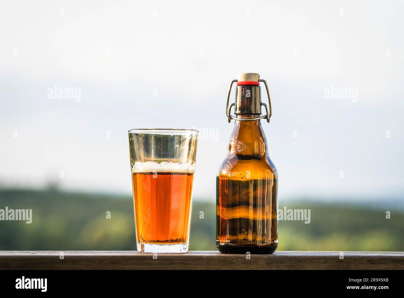 Glas Bier neben einer Flasche auf einem Regal in der freien Natur Stockfoto