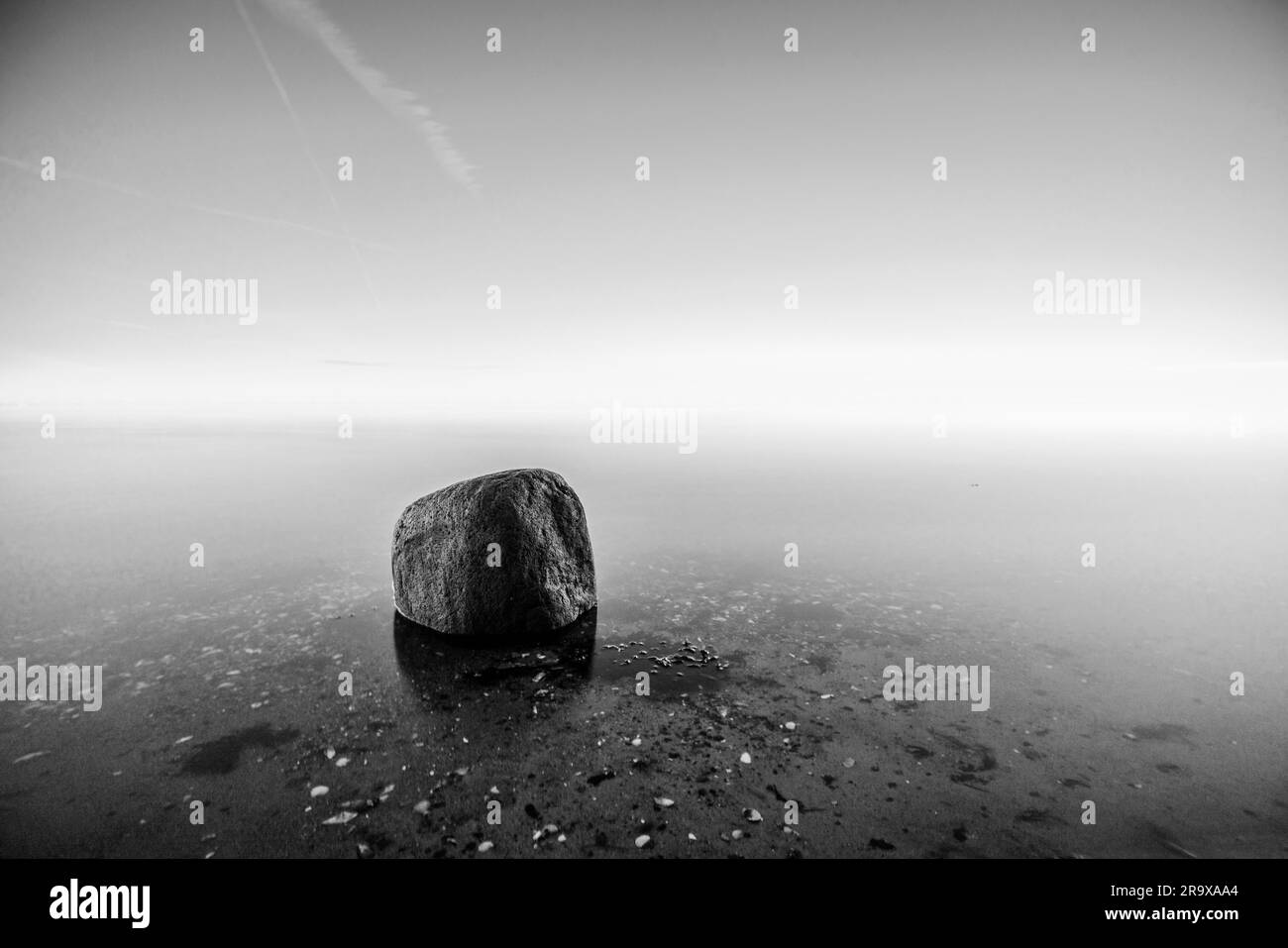 Single Rock im Wasser am Meer in schwarz Und weiße Farben Stockfoto