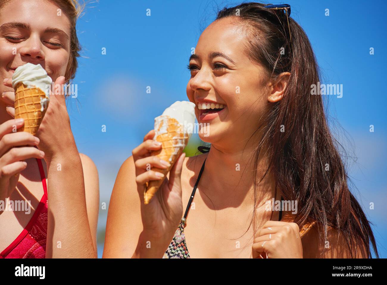 Lachend, Freunde und Frauen essen Eiscreme im Freien, haben Spaß und Spaß im Sommerurlaub. Eis, Mädchen und glückliche Leute mit Dessert, Vanille oder Stockfoto