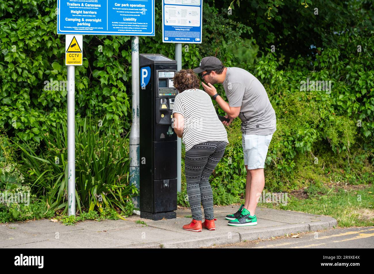 Personen, die für das Parken auf einem Parkplatz an einem Automaten bezahlen. Parken bezahlen, Parkschein kaufen. In England, Großbritannien. Stockfoto