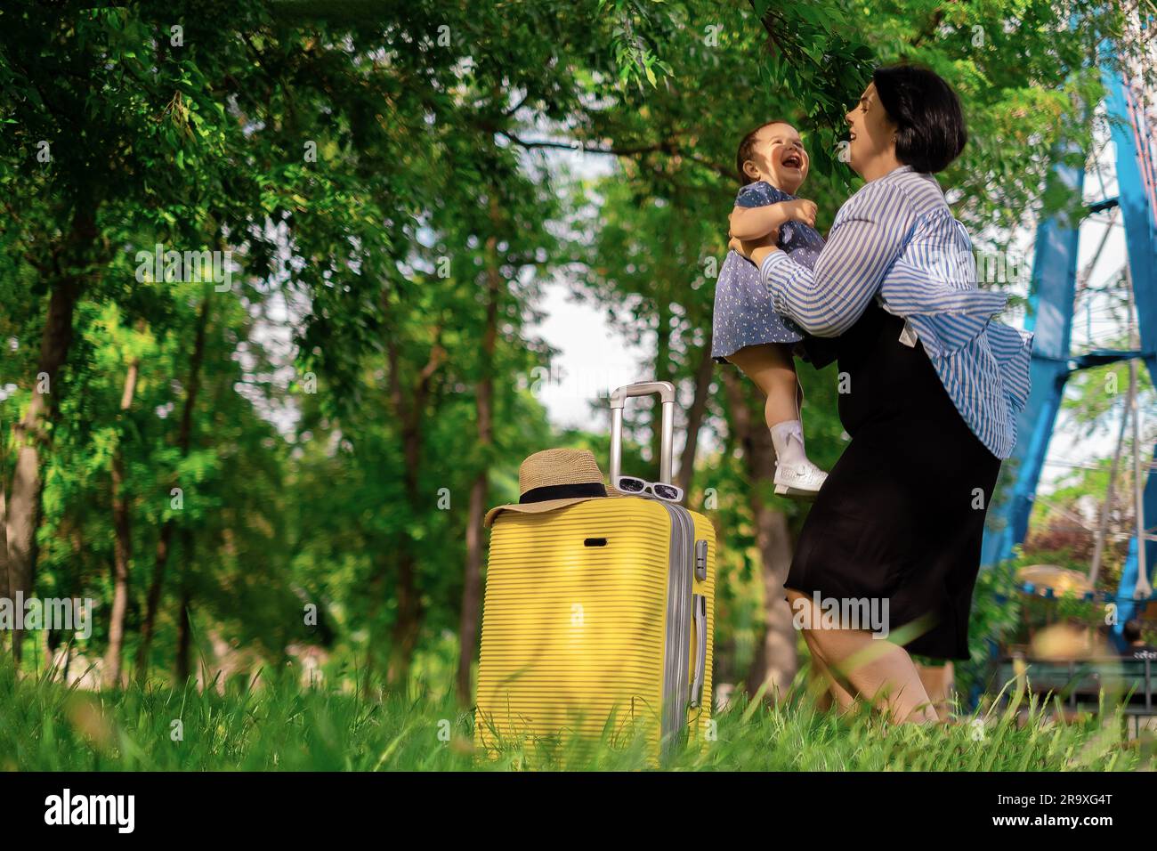 Mom und Tochter bereiten sich auf die Reise vor. Ein kleines Mädchen sitzt auf einem gelben Koffer. Geh auf eine Reise, entspann dich auf See, sammle Semodans im Urlaub Stockfoto