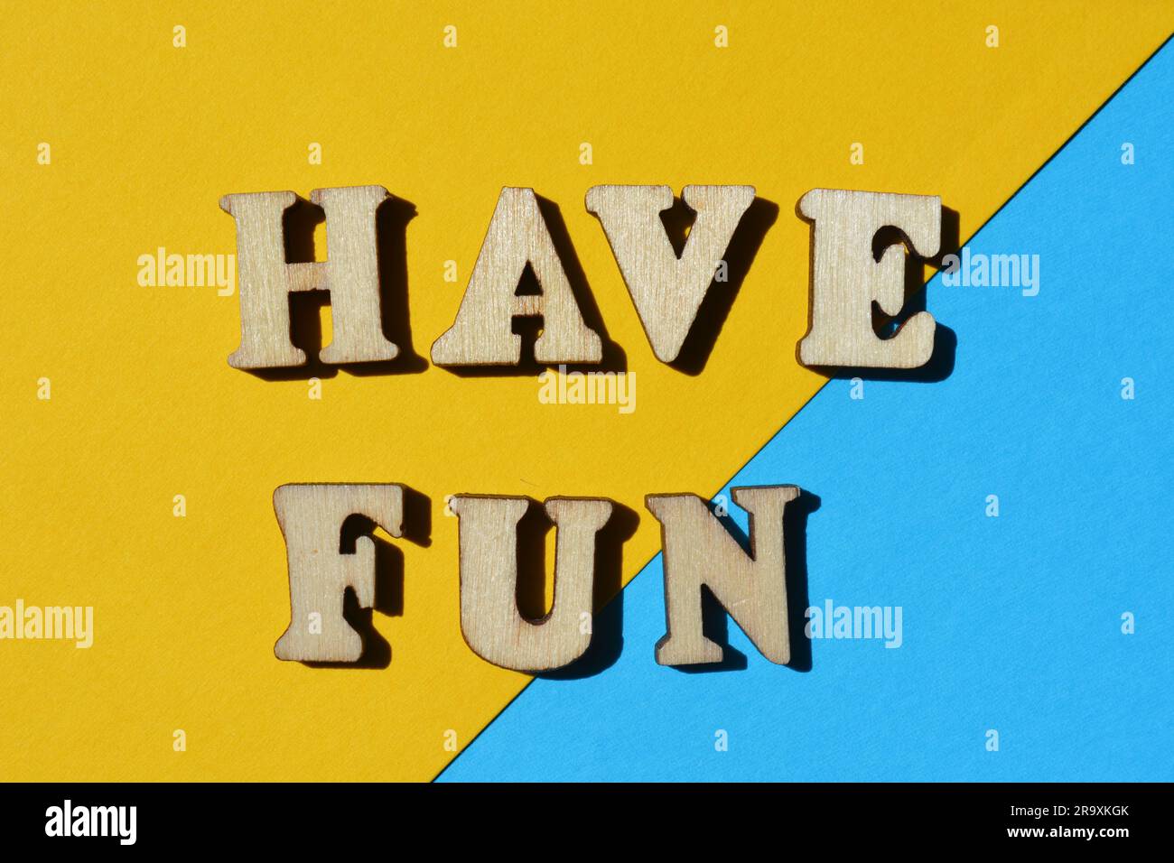Haben Sie Spaß, Wörter in hölzernen Buchstaben isoliert auf blauem und gelbem Hintergrund als Bannerüberschrift Stockfoto