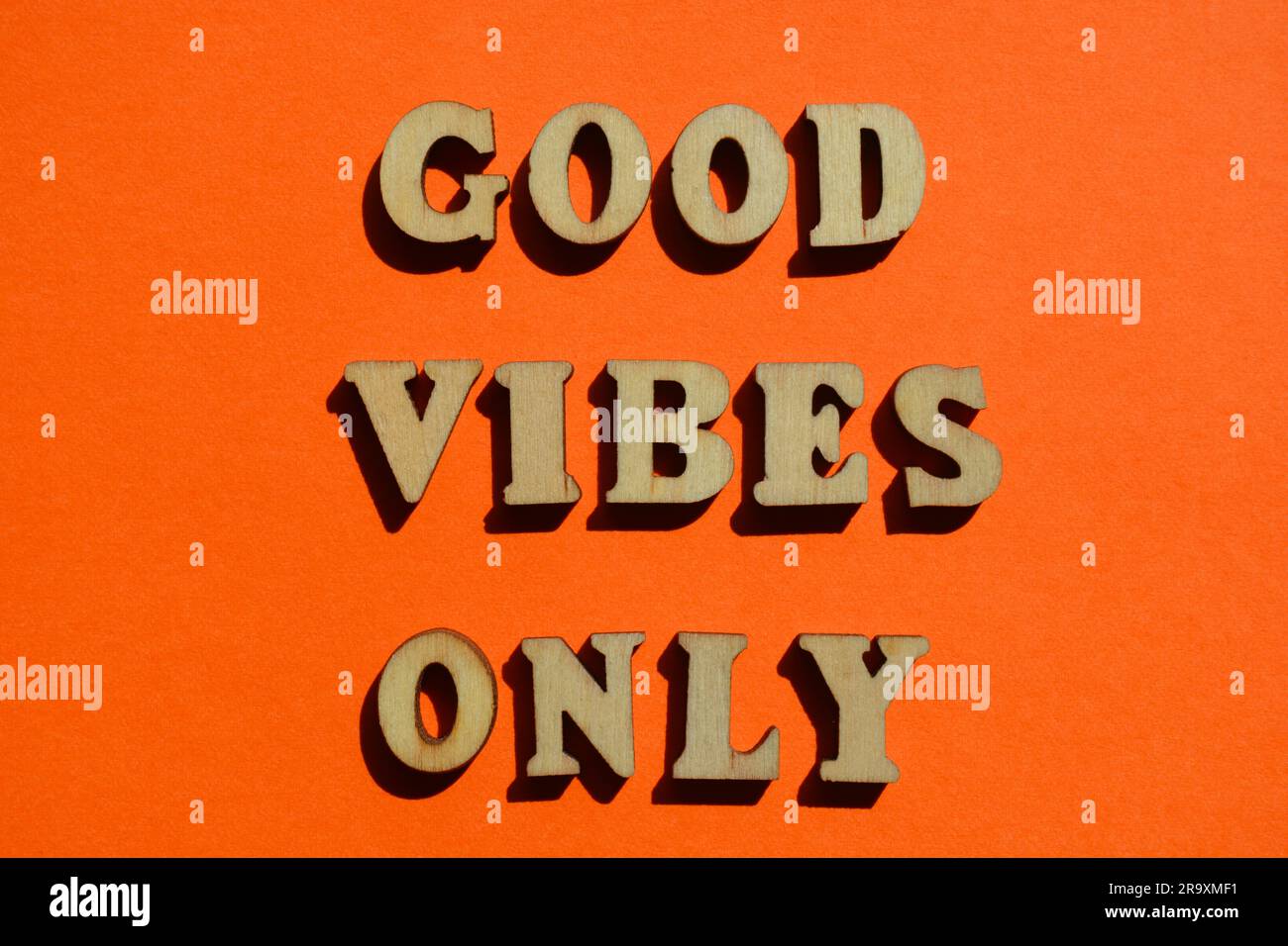 Nur gute Vibes, Wörter in hölzernen Buchstaben isoliert auf hellem orangefarbenen Hintergrund Stockfoto