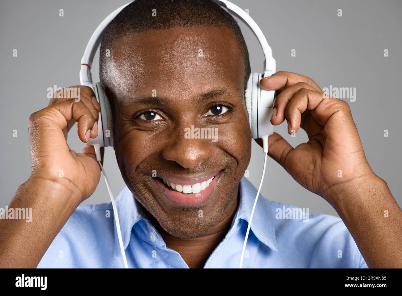 Musik, Porträt eines Schwarzen mit Kopfhörern und vor Studiohintergrund, der gerne Radio hört. Podcast oder Audio, Sound-Playlist oder Lächeln und Stockfoto