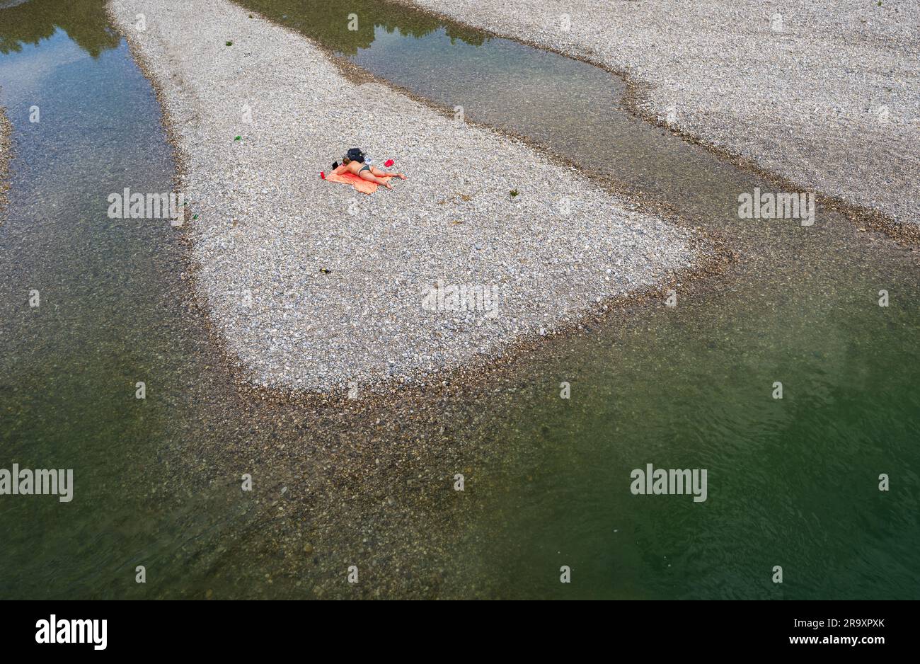 München, Deutschland. 29. Juni 2023. Eine Frau genießt das warme Wetter am Kiesufer der Isar, die einst durch die bayerische Hauptstadt fließt. Kredit: Peter Kneffel/dpa/Alamy Live News Stockfoto