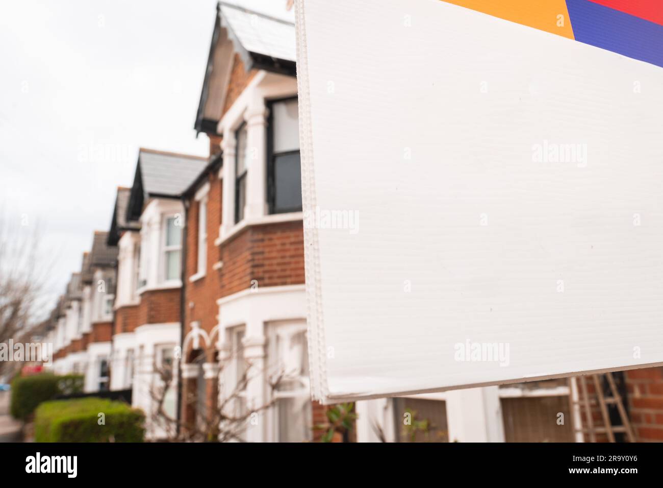 Britische Häuser mit leerem Immobilienmakler-Schild mit Platz für Text Stockfoto