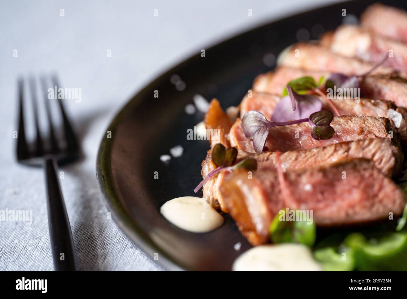 Rinderfilet auf schwarzem Teller mit schwarzer Gabel. Selektiver Fokus. Stockfoto