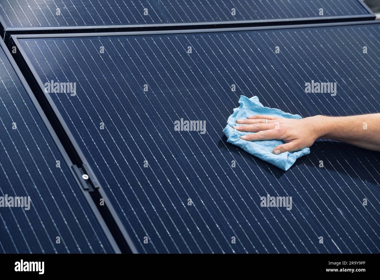 Manuelles Reinigen eines Sonnenkollektors mit einem Tuch Stockfoto