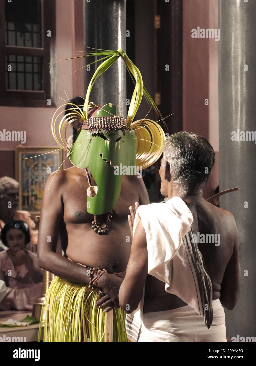 Ein maskierter Theyyam-Künstler, der im Namen eines hindu-Tempels für eine religiöse Zeremonie unter den Anhängern in der Öffentlichkeit auftritt Stockfoto