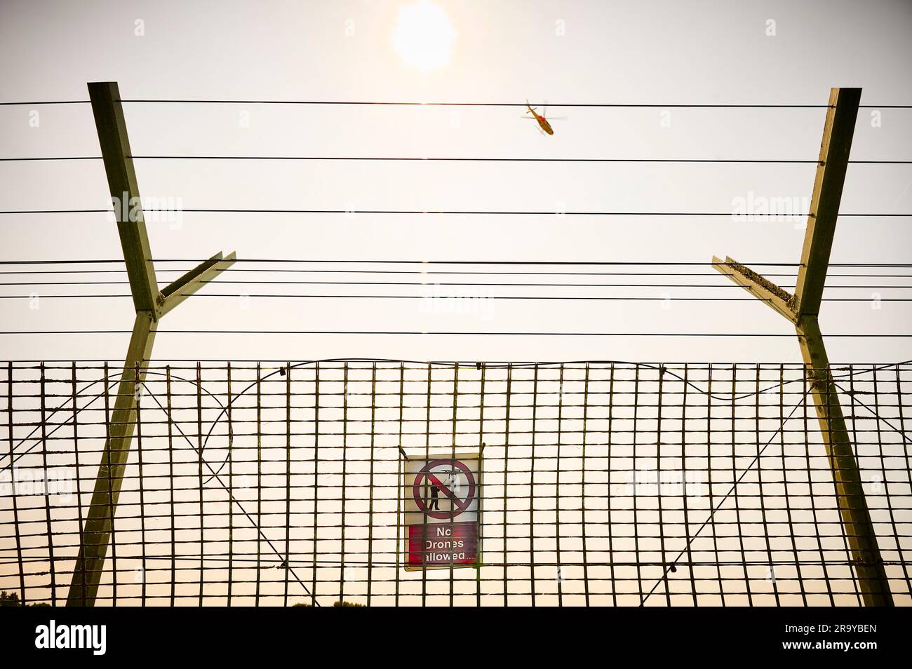 Keine Drohnen erlaubt Schild und Hubschrauber fliegen über den Flughafenzaun Stockfoto