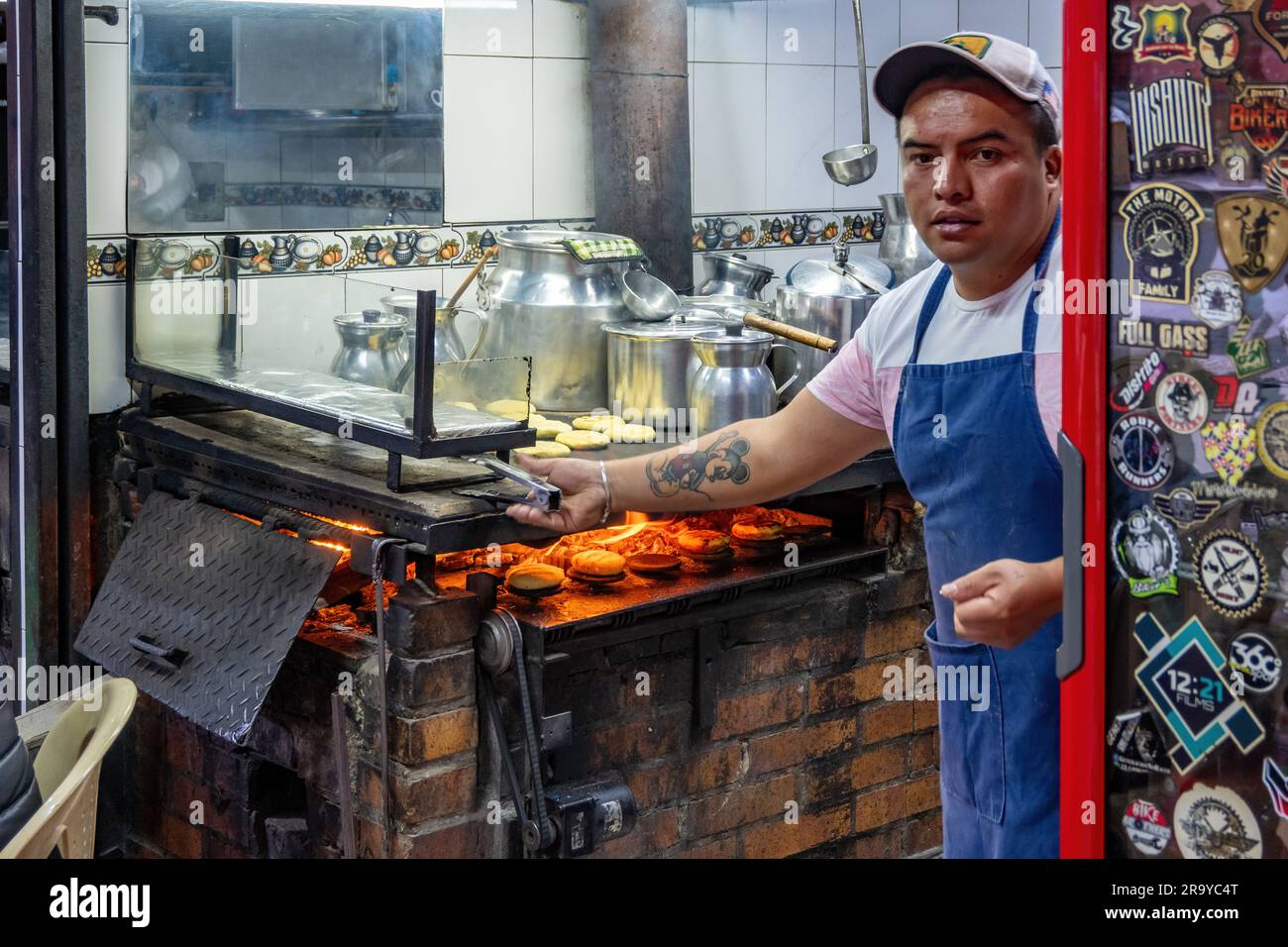 Ein Mann, der in einem kleinen Restaurant Aripipas auf offenem Feuer brät. Kolumbien, Südamerika. Stockfoto