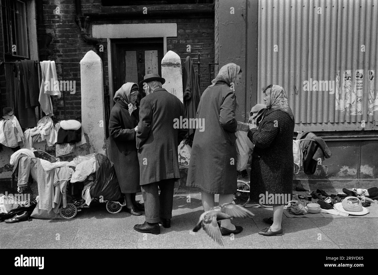 Armut East London 1970s UK. Arbeitslose Frauen verkaufen alte Kleidung und Bric-a-brac von Kinderwagen, um ihr dürftiges Leben zu ergänzen. Eine trägt ihr Kopftuch über ihrem Hut, um die Kälte fernzuhalten. Whitechapel, London, England 1972 70er Jahre HOMER SYKES. Stockfoto