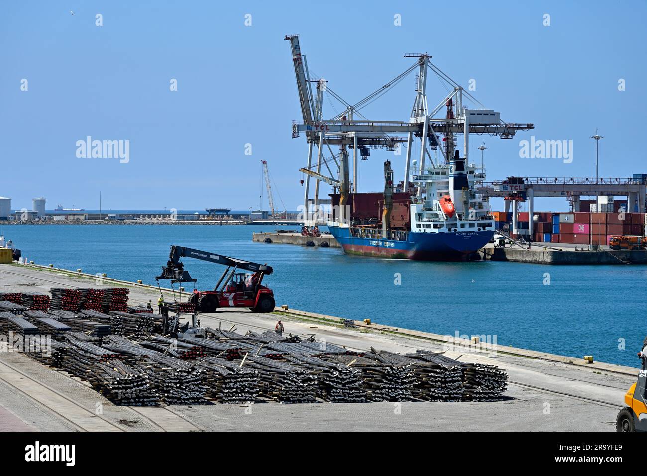 Hafenseite des Docks mit Stahlstangen und Containerschiff, das auf der anderen Seite des Wassers entladen wird, Porto, Portugal Stockfoto