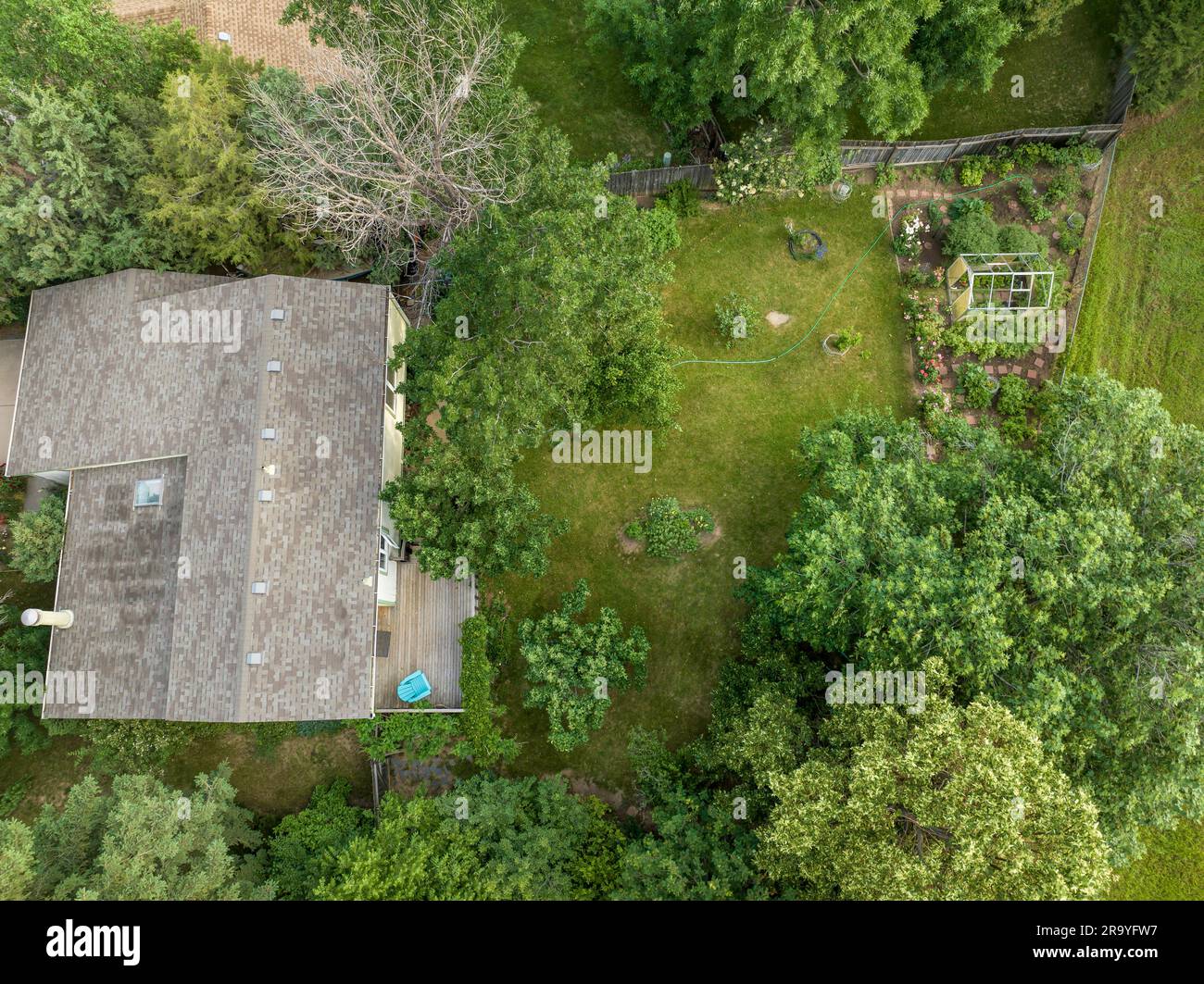 Luftaufnahme auf ein Wohnhaus und einen grünen Hinterhof mit Garten in Sommerlandschaft Stockfoto