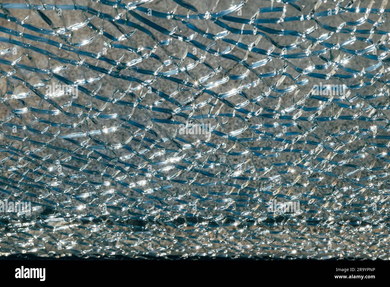 Das Sonnenlicht glänzt in Nahaufnahme durch ein rissiges Glasmuster auf dem Fenster und zeigt zerschmetterte Details eines hellen Tages. Stockfoto