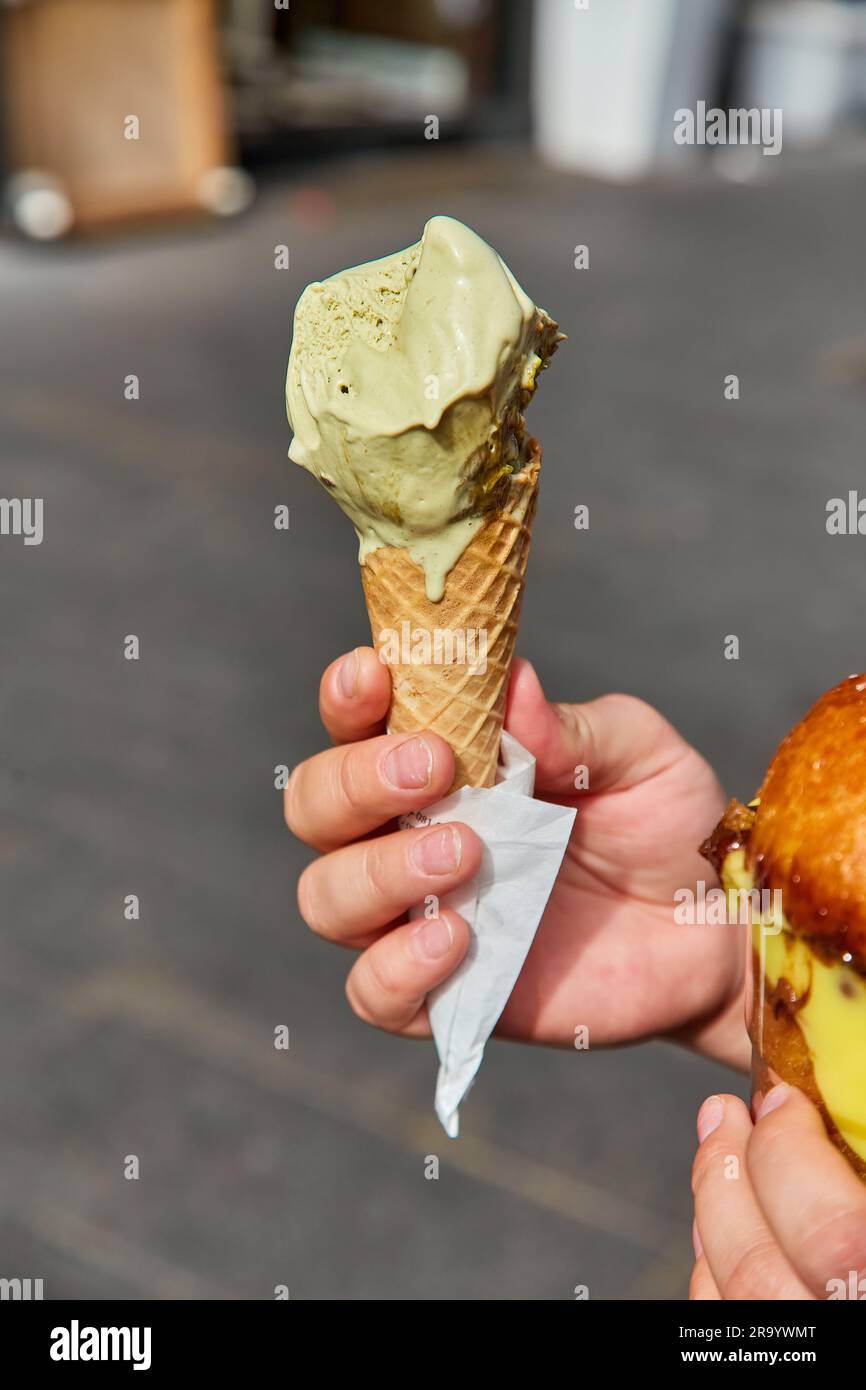 Eiskegel mit Minzpistazienfarbe in der Stadt. Sommerliche kalte Erfrischung. Köstliches Essen. Stockfoto