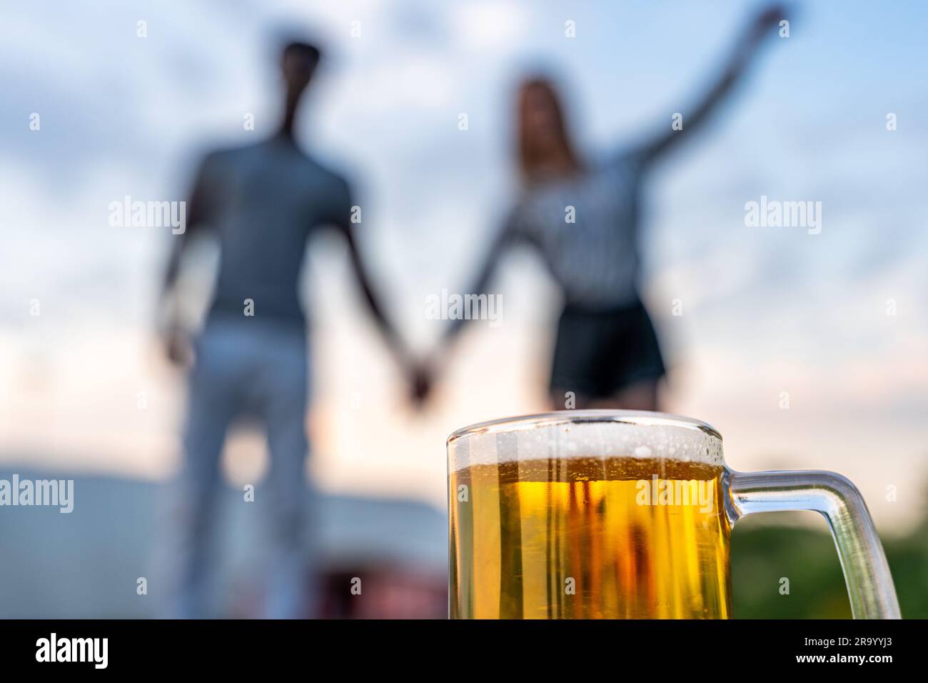 Nahaufnahme eines Glases Bier vor einem jungen, multiethnischen Paar von Liebhabern, verschwommen im Hintergrund Stockfoto