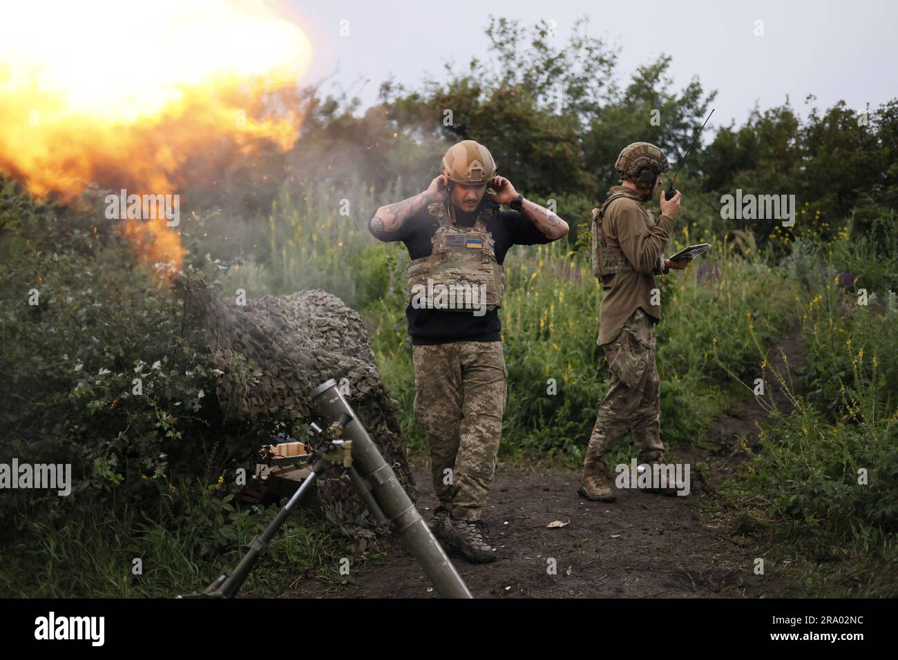 A Ukrainian servicemen of the 3rd separate assault brigade speaks on the radio while another serviceman is firing 82mm mortar towards Russian positions at the frontline near Bakhmut, Donetsk region, Ukraine, Thursday, June 29, 2023. (AP Photo/Alex Babenko) Stockfoto