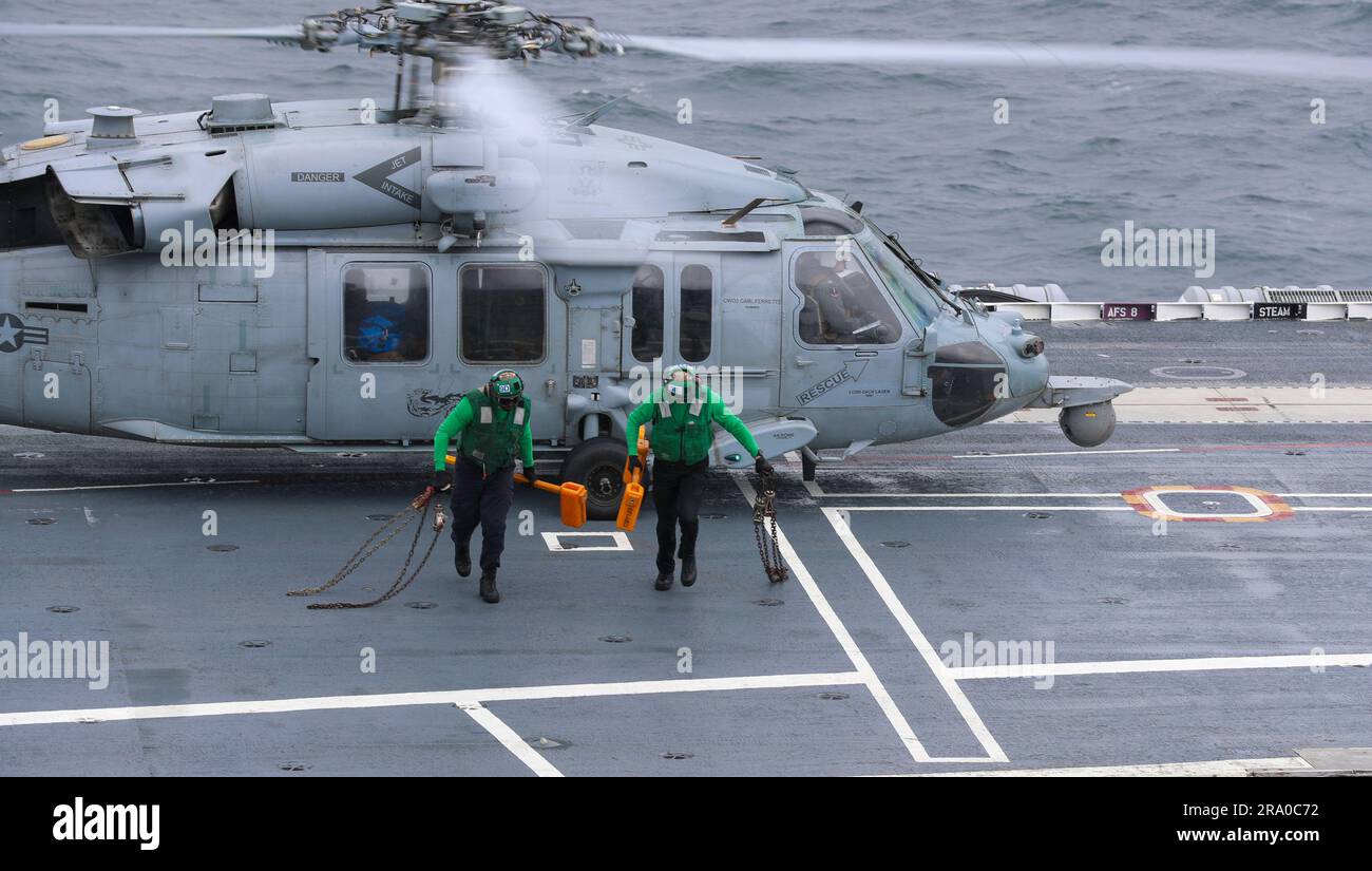 Matrosen, die der Division Air departmentÕs V-2 an Bord des Flugzeugträgers der Nimitz-Klasse USS George Washington (CVN 73) zugeteilt wurden, entfernen Keile und Ketten, bevor ein MH-60s Seahawk Hubschrauber, der der ÒDragonslayersÓ of Helicopter Sea Combat Squadron 11 (HSC-11) zugeteilt wurde, auf dem Flugdeck im Atlantik startet, 21. Juni 2023. George Washington führt derzeit die Zertifizierung des Cockpits durch, eine Bewertung der Fähigkeiten der shipÕs, Flugzeuge sicher zu starten und zu Bergen. (USA Geburtsdatum: 21.10.1956 Stockfoto