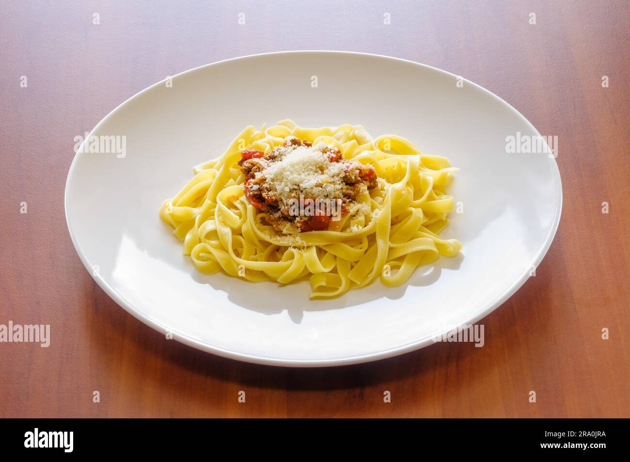 Bandnudeln mit Bolognese Ragout mit Parmesan, in einem weißen Teller Stockfoto
