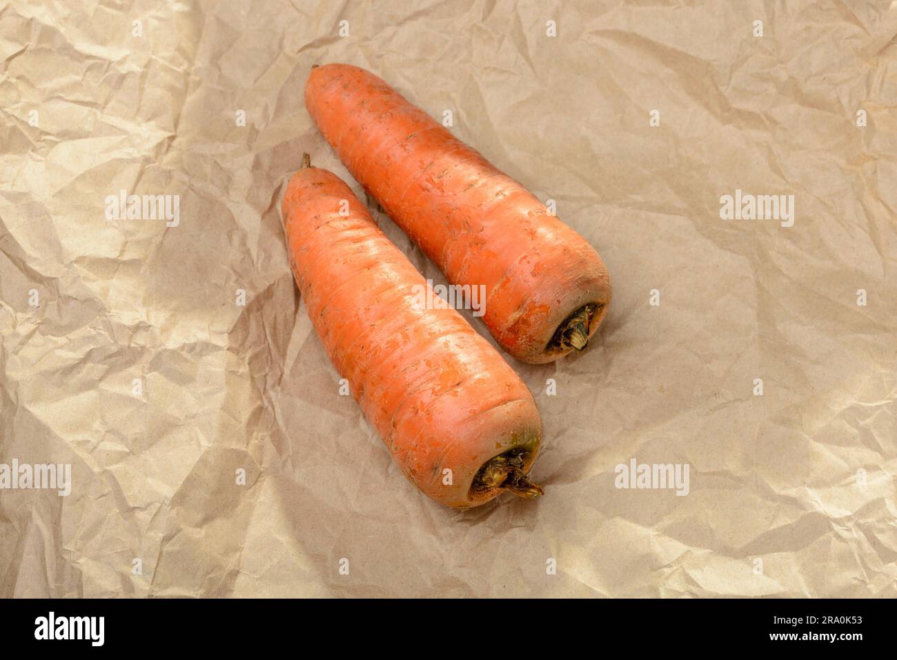 Zwei schöne natürliche Karotten auf einem braunen Kraftpapier Stockfoto