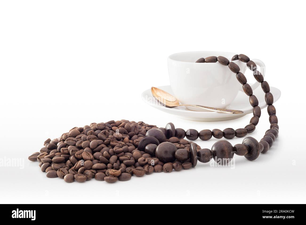 Eine Kaffeetasse aus weißem Porzellan mit einer halskette aus afrikanischen Holzperlen und Kaffeebohnen aus Elfenbeinküste Stockfoto