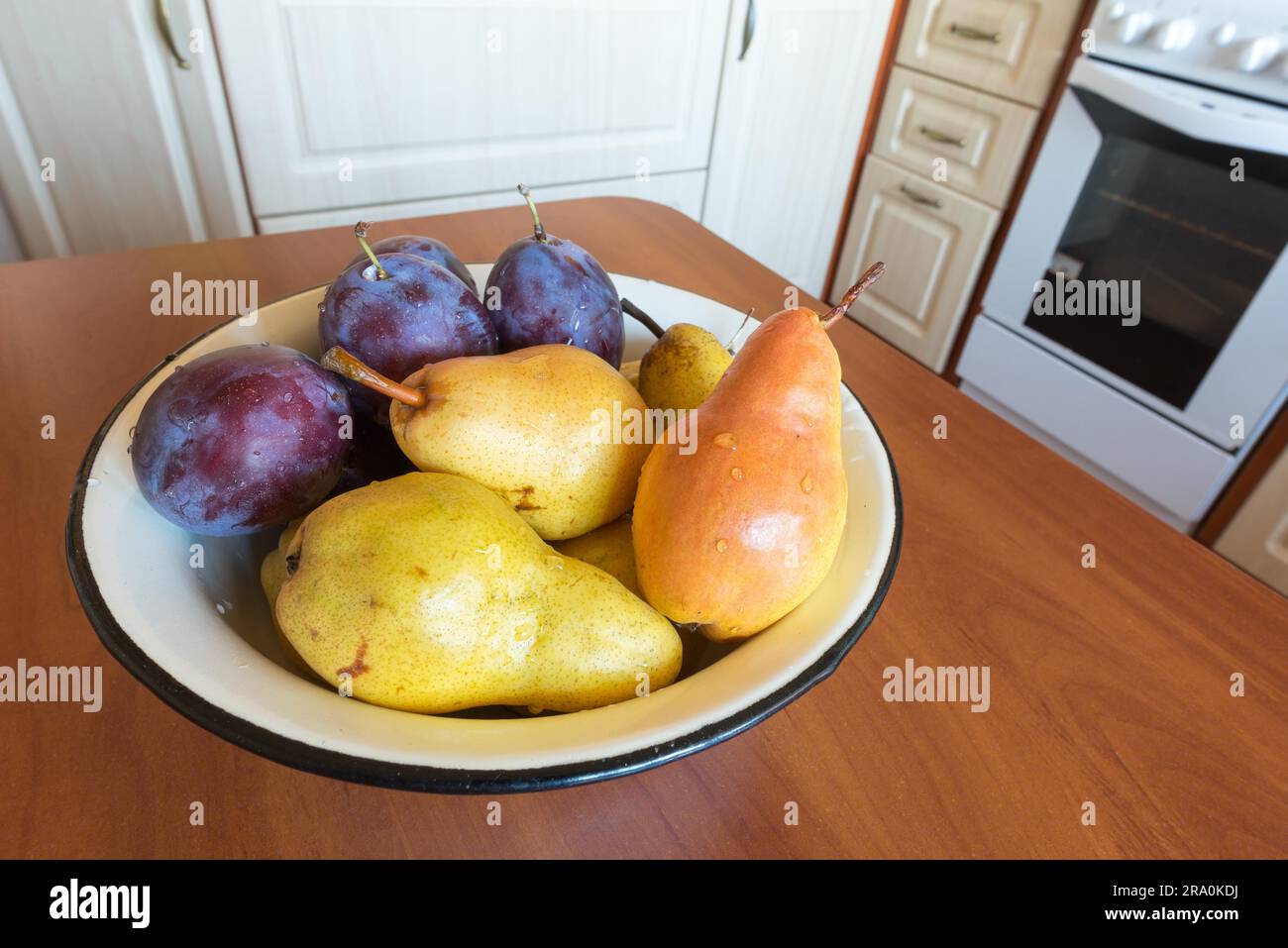 Tisch mit einer Schüssel voller sauber Birnen und Pflaumen in der Küche Stockfoto