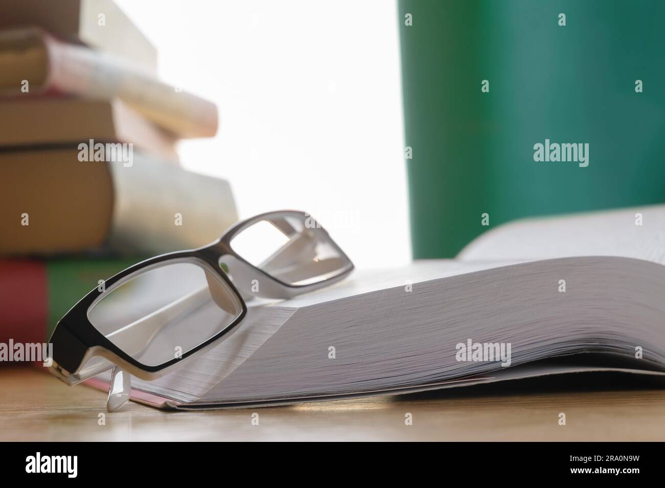 Brille aufsetzen ein großes Buch der Geschichte, vor einem Fenster mit Vorhang Stockfoto