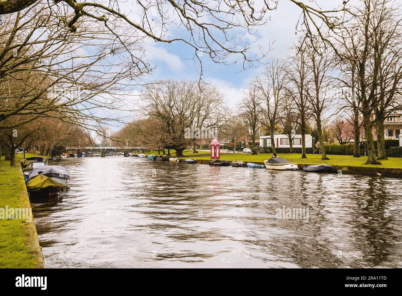 Einige Boote im Wasser und Bäume auf der anderen Seite des Flusses ohne Blätter oder Zweige Stockfoto