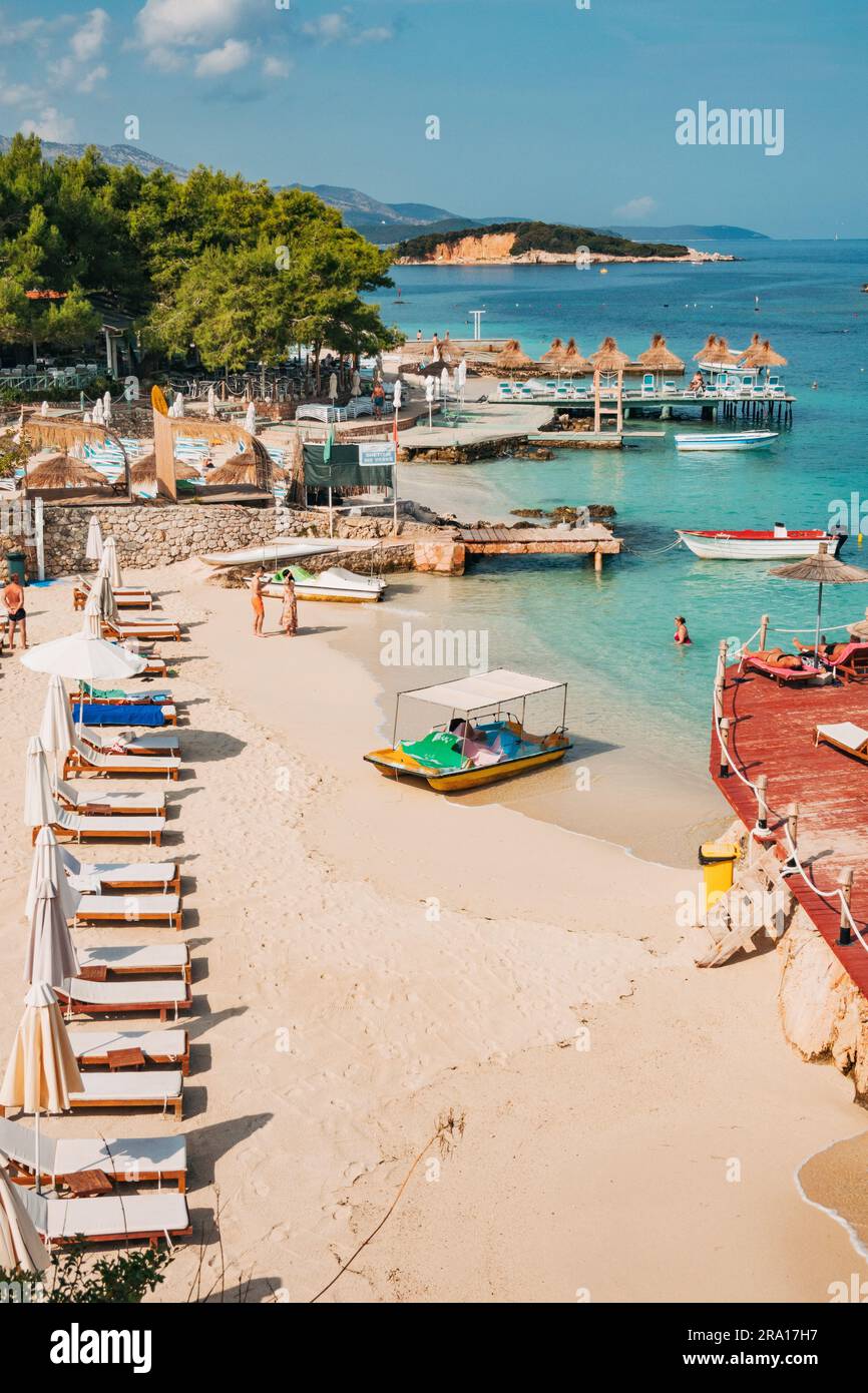 Sonnenliegen, Sonnenschirme und türkisblaues Wasser warten auf Touristen am Rilinda Beach, Ksamil, Albanien Stockfoto