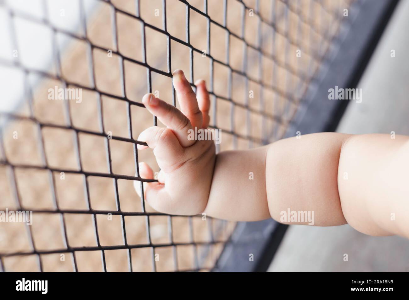 Kinderhände mit Hintergrund aus Stahlkäfig für Werbung und Tapeten in der Babysicherungs- und -Schutzszene. Tatsächliche Bilder in Dekorationsideen Stockfoto