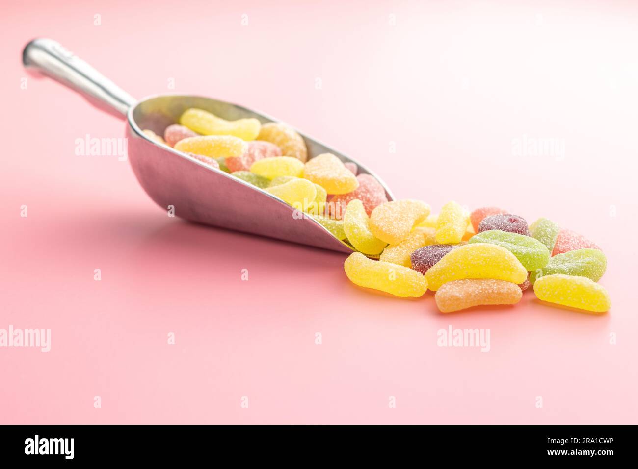 Mischung aus Fruchtgelee-Süßigkeiten in der Schaufel auf pinkfarbenem Hintergrund. Stockfoto