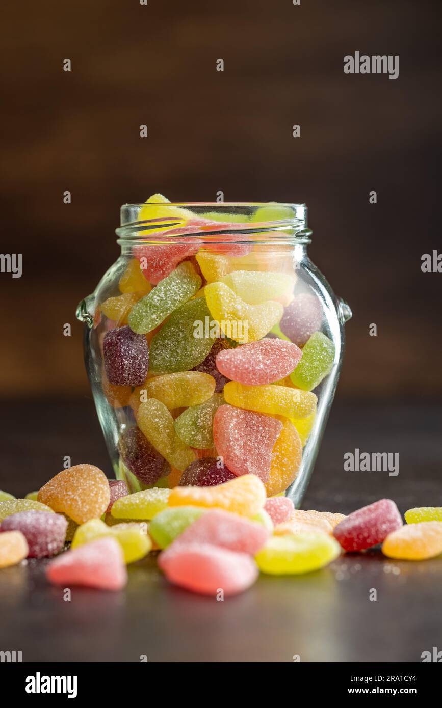 Mischung aus Fruchtgelee-Süßigkeiten im Glas auf dem schwarzen Tisch. Stockfoto