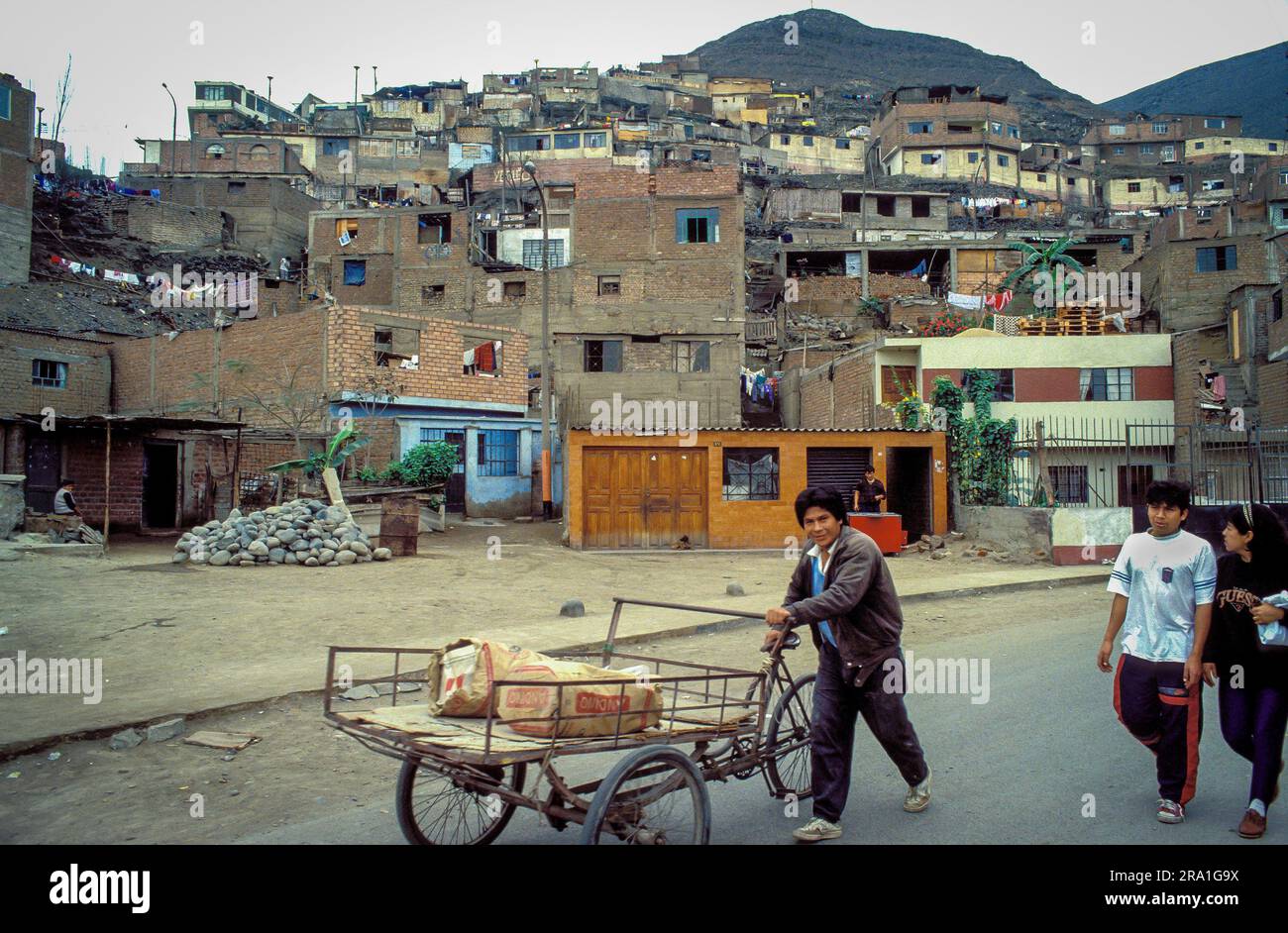 Peru, Lima; ein Mann, der mit einem Fahrrad in einem Außenbezirk von Lima läuft. Stockfoto