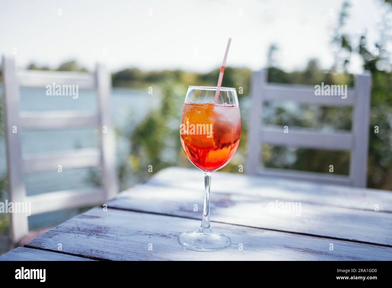 Elegantes langstieliges Glas Spritz aperol mit einer Scheibe Orange auf einem weißen Holztisch. Ein Becher leckerer Cocktails mit Sekt und Orangensaft Stockfoto