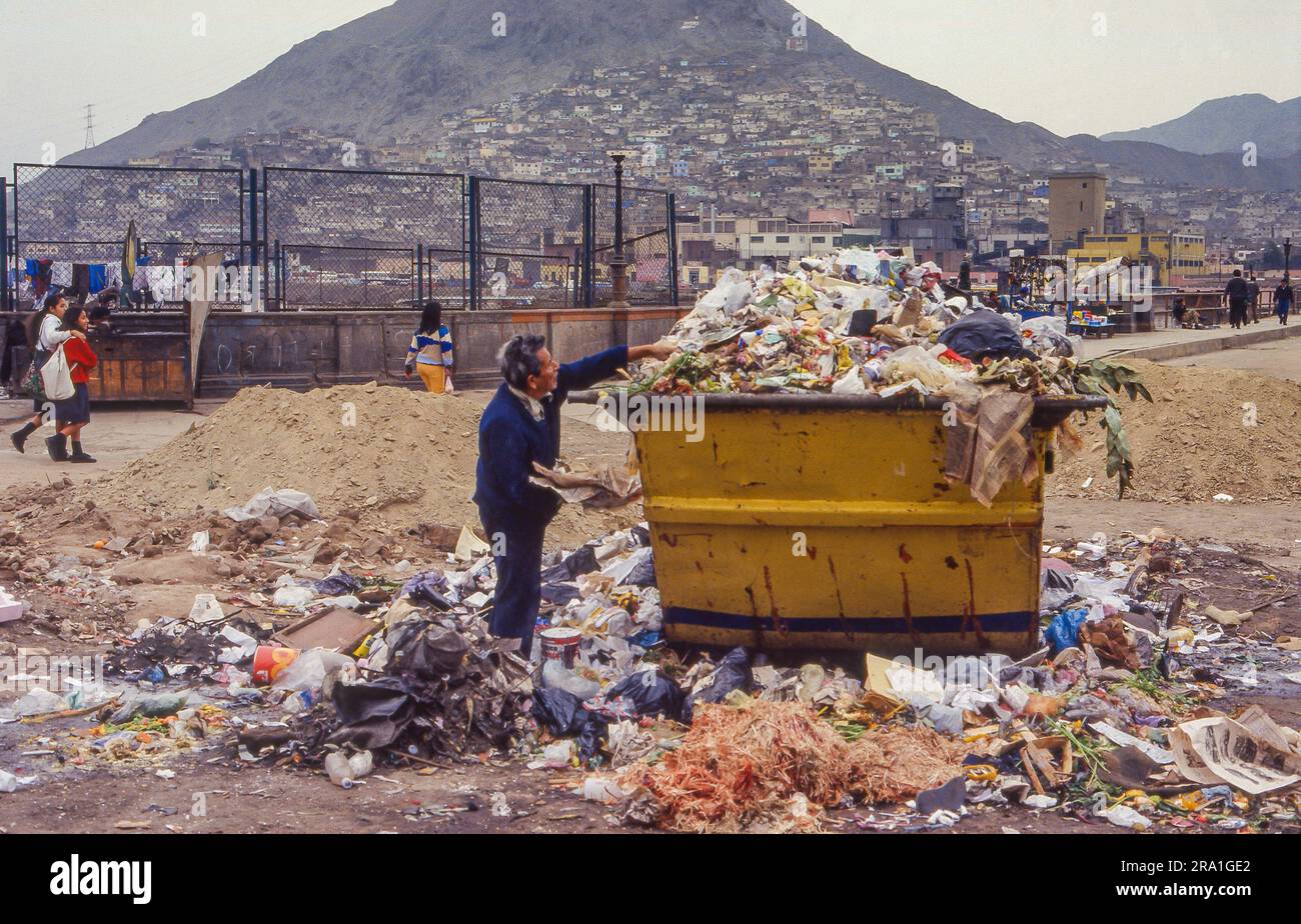 Peru, am Stadtrand von Lima sucht ein Landstreicher in einem Mülleimer nach etwas Nützlichem. Stockfoto