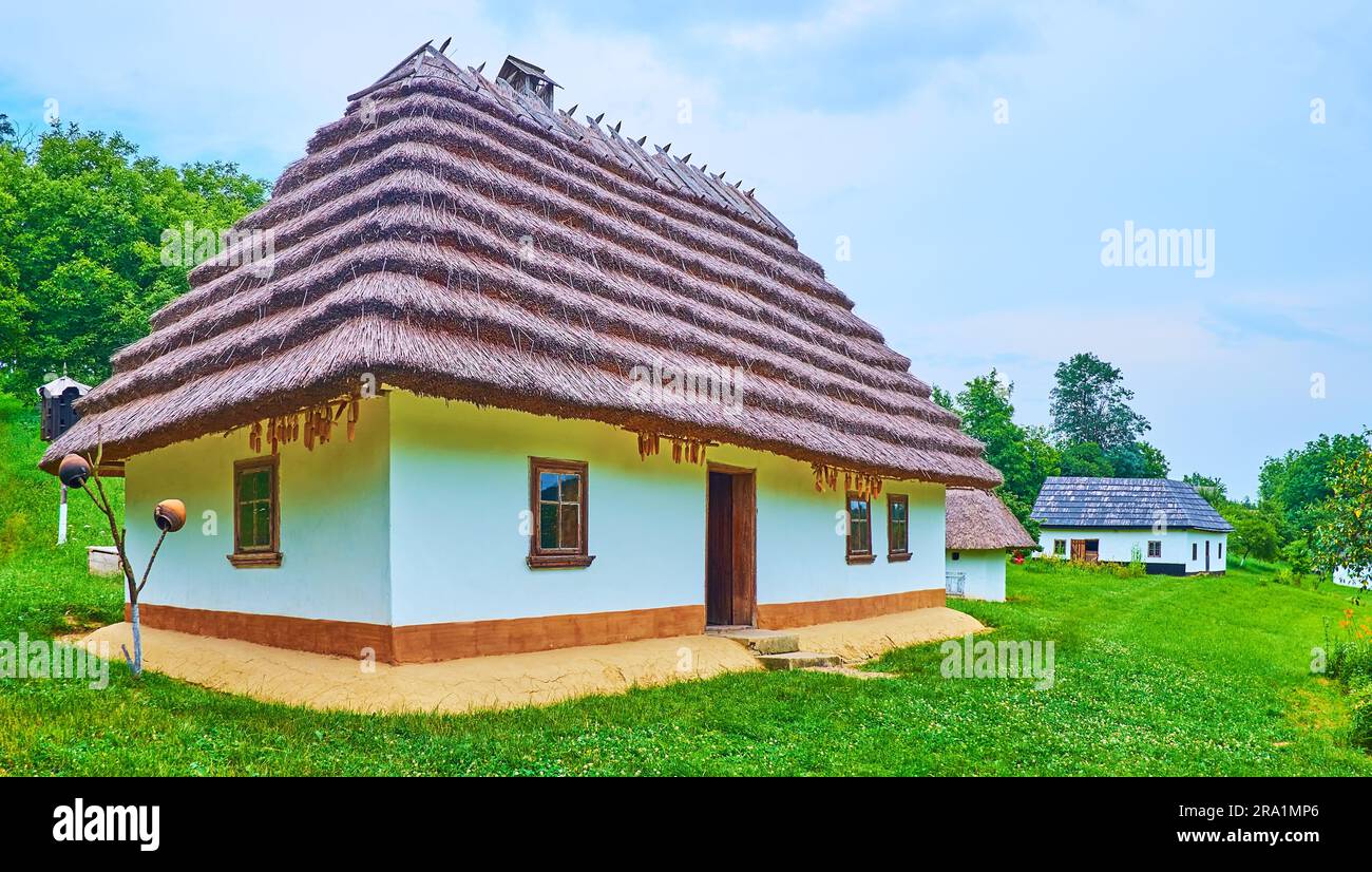 Panorama des wunderschönen bukovinischen Bauernhofs mit traditionellem weiß getünchten Haus, bedeckt mit gestuftem Strohdach, Chernivtsi scansen, Ukraine Stockfoto