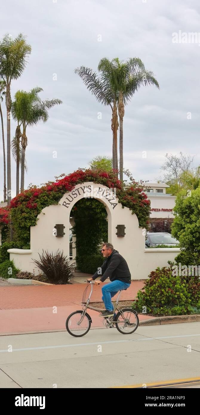 Ein Radfahrer, der am Eingang des mit Blumen überdachten Bogens vorbeifährt, führt zum Rusty's Pizza Restaurant 111 State Street Santa Barbara California USA Stockfoto