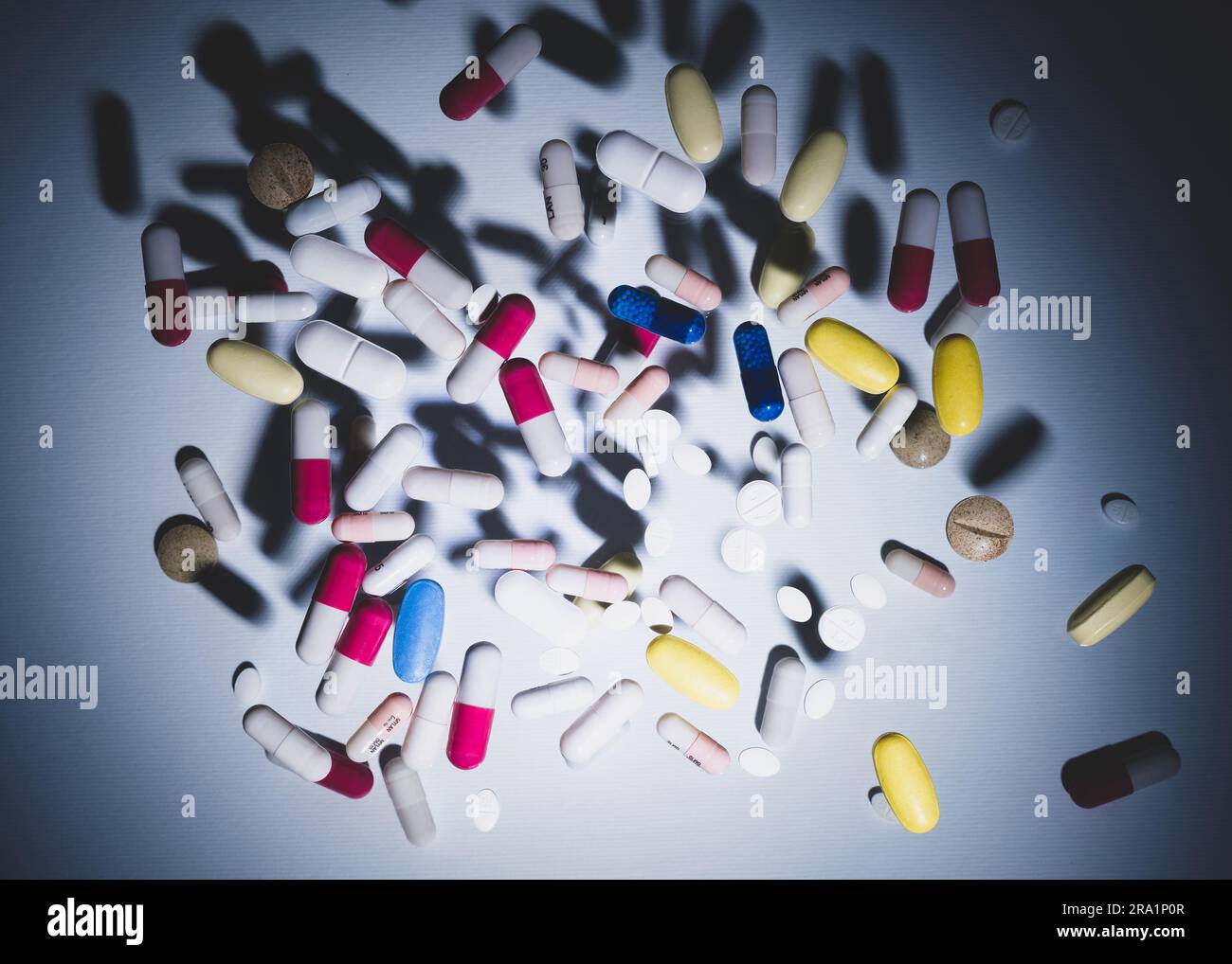 Tabletten und Kapseln, die auf zwei Ebenen auf einer Glasplatte platziert werden, erzeugen eine Wirkung der Suspension in der Luft, kreatives Konzept des Drogenmissbrauchs. Stockfoto