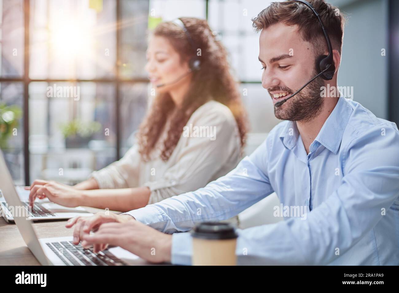 Attraktiver, männlicher Kundendienstmitarbeiter, der als Telemarketer im Callcenter-Büro arbeitet. Stockfoto